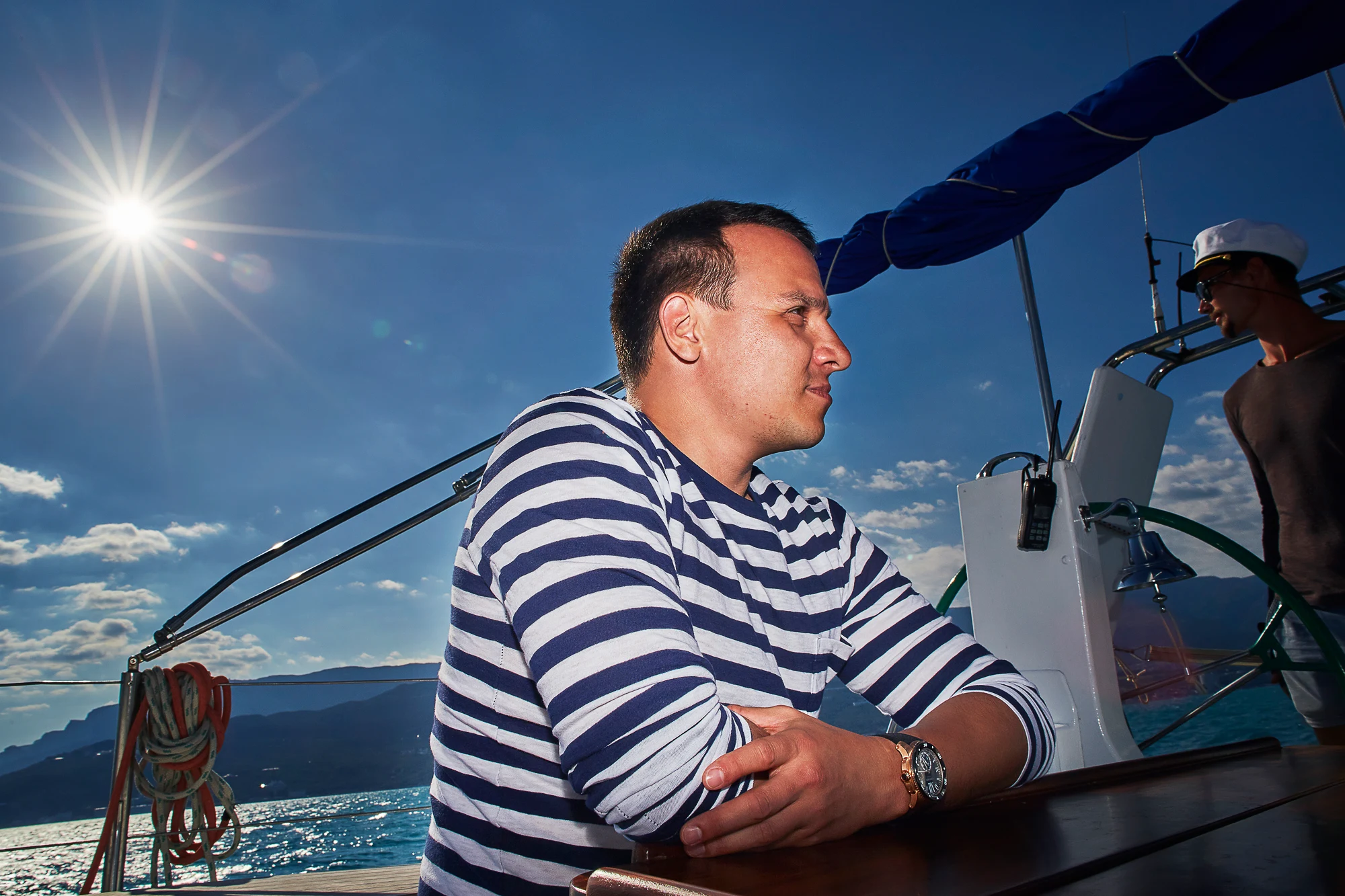 Pavel Manylov in a striped sailor shirt relaxing on the deck of a sailing yacht in Italy