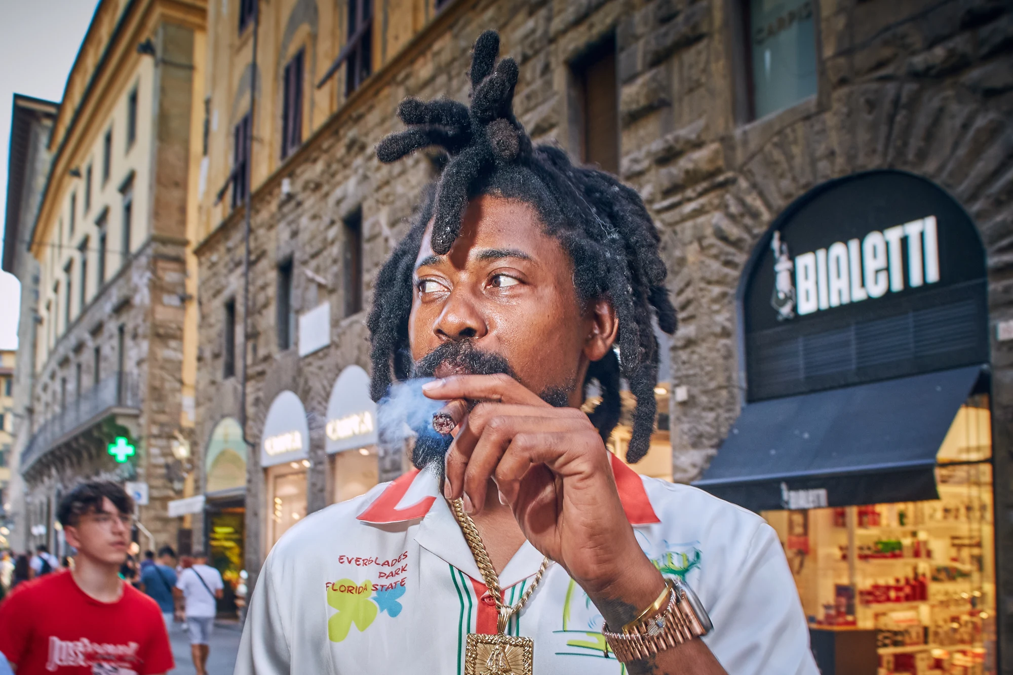 Street portrait of a man with dreadlocks smoking a cigar in Florence