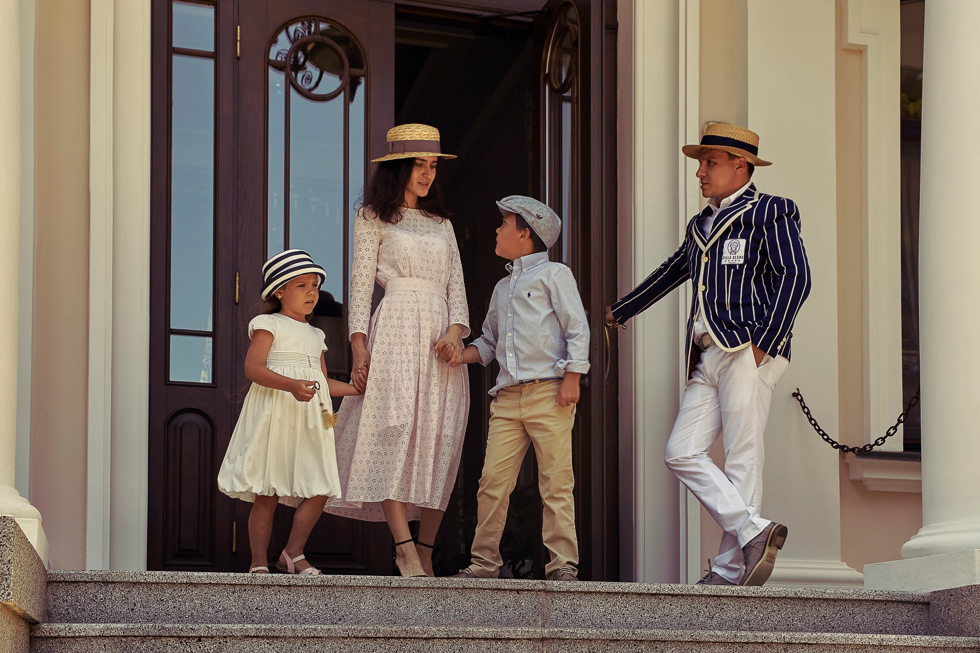 Stylish family with two children posing on the steps of a classic building in Italy
