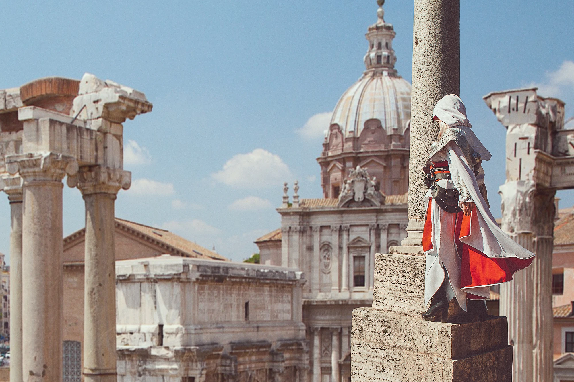 Assassin’s Creed cosplayer standing on a column above ancient Roman ruins with city view