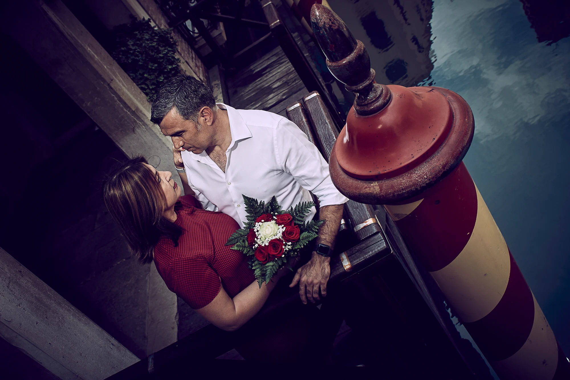 Romantic couple with bouquet embracing on a wooden pier in Venice