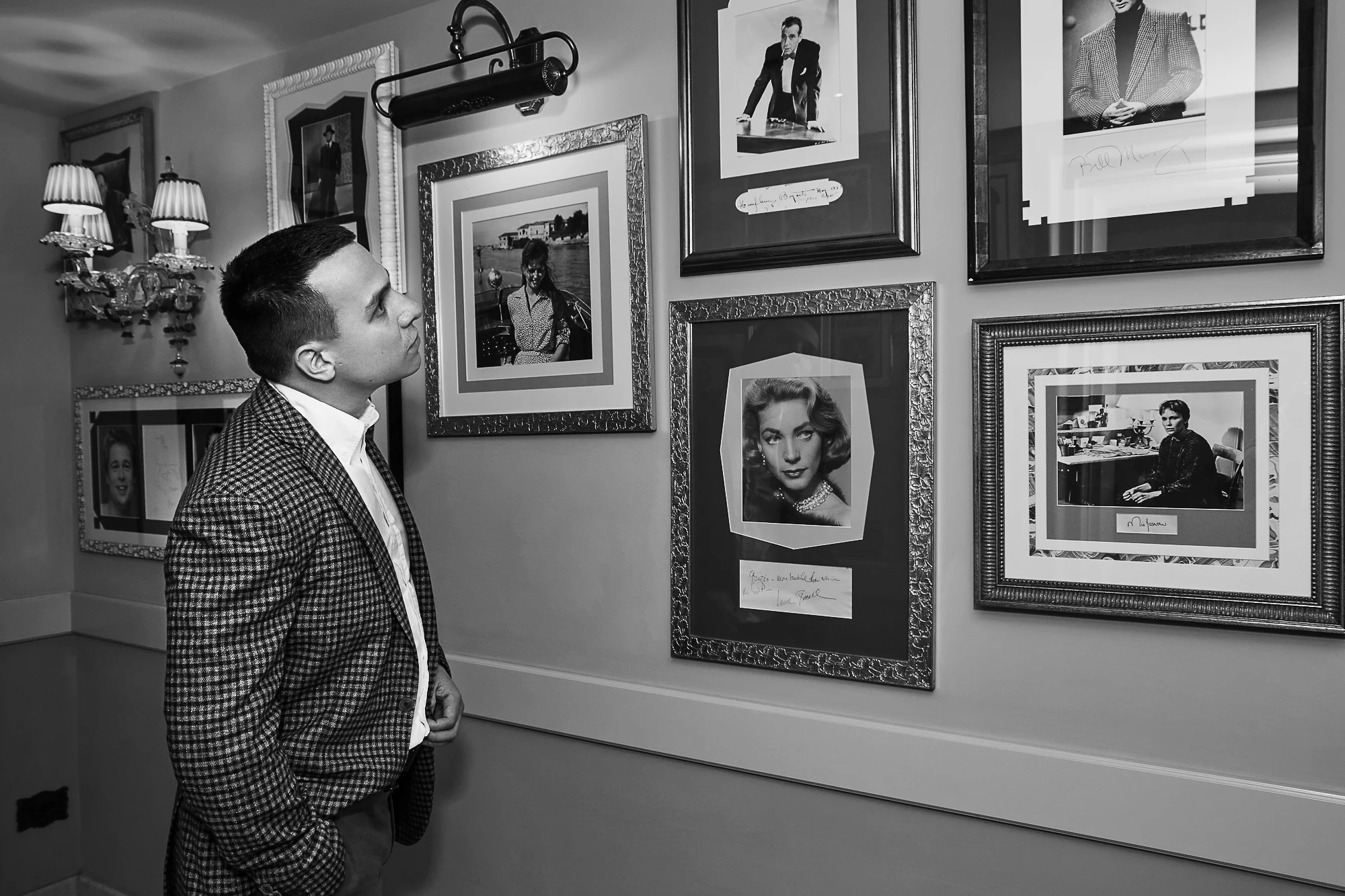 Man in classic jacket looking at framed celebrity portraits at Gritti Palace in Venice (Pavel Manylov)
