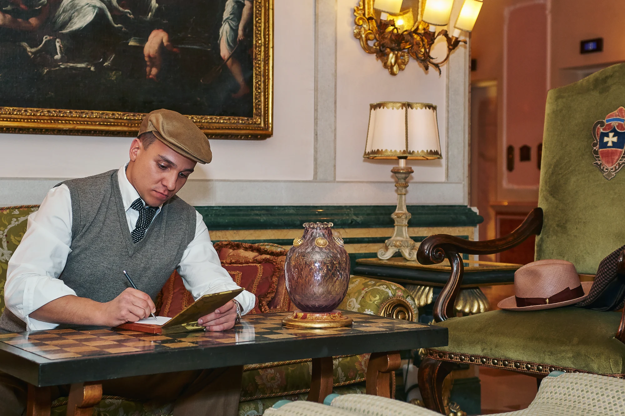 Man in retro style writing at a table inside Gritti Palace Venice (Pavel Manylov)