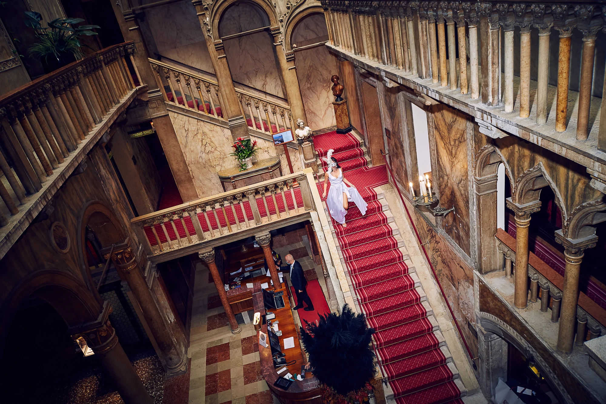 Elegant woman in evening dress descending the grand staircase of Hotel Danieli in Venice