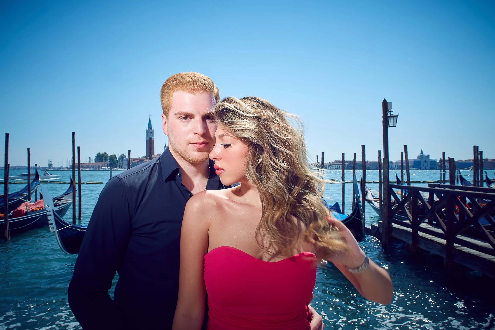Romantic couple standing by gondolas with San Giorgio Maggiore in Venice