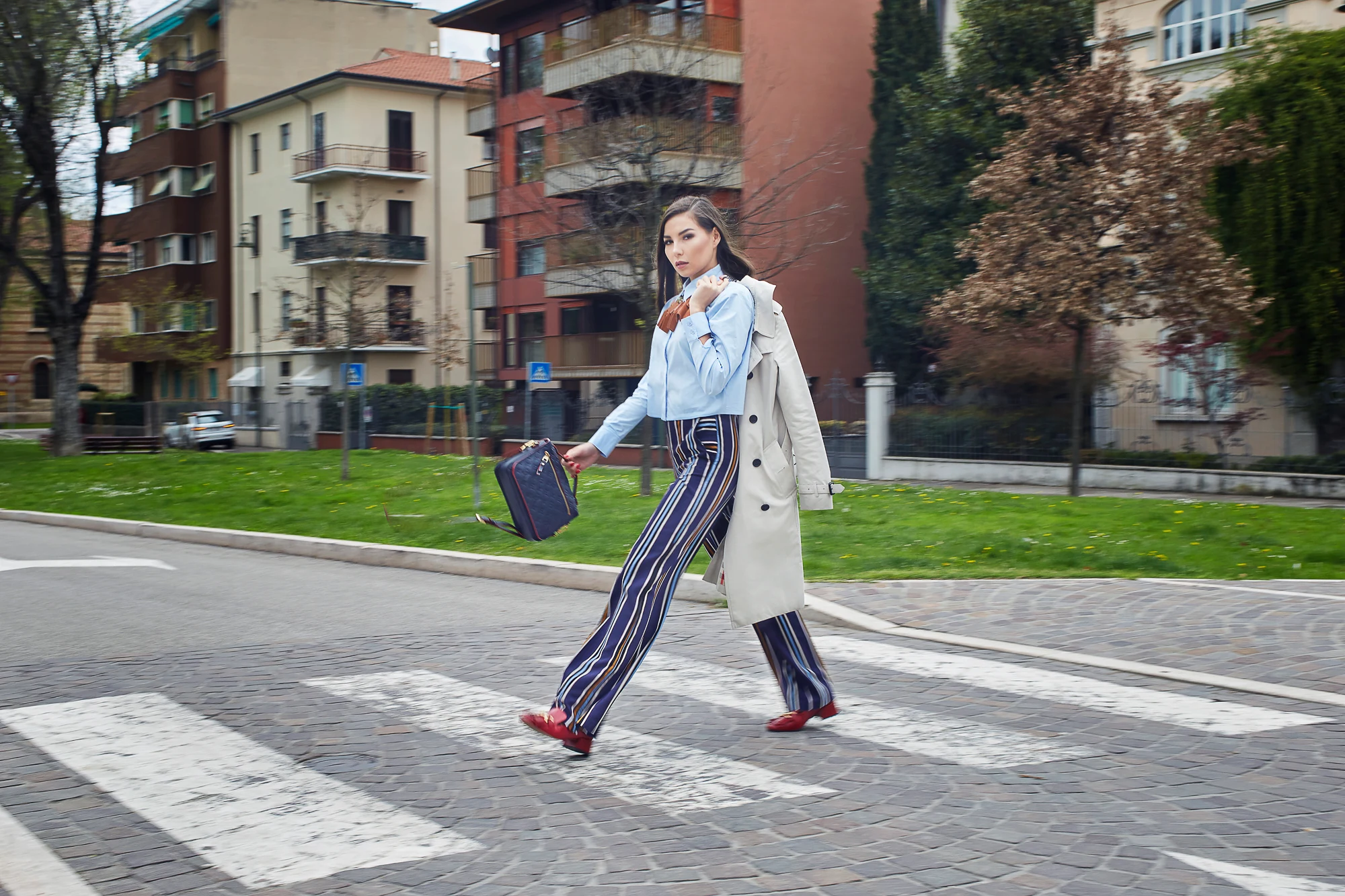 Stylish woman walking across a crosswalk in Verona with residential buildings behind (Karina Nigay)