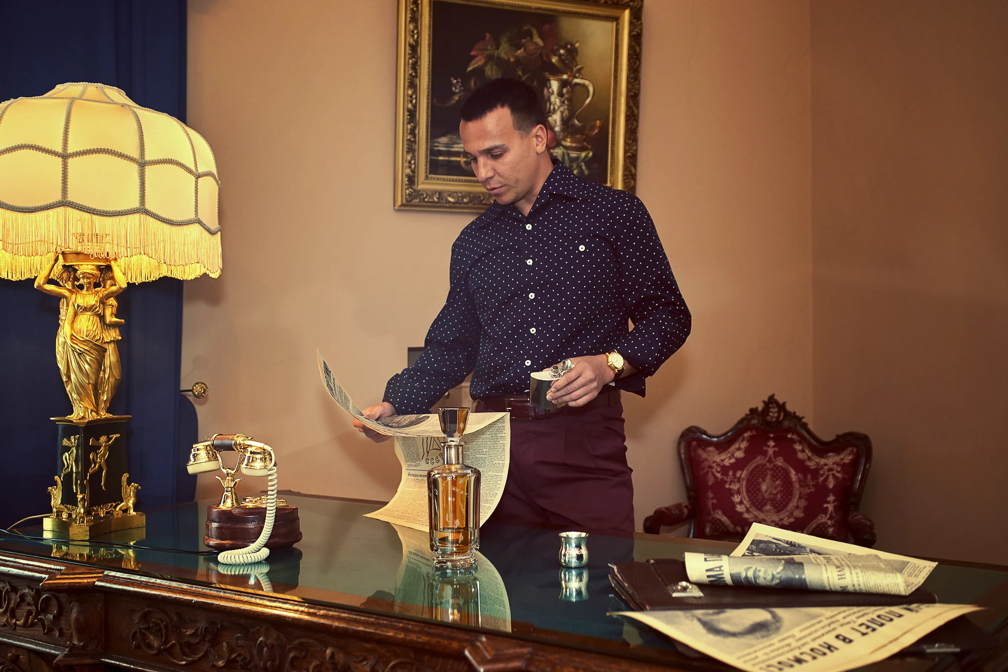 Retro style Pavel Manylov male portrait in an elegant luxury hotel suite with newspapers and whiskey on the desk