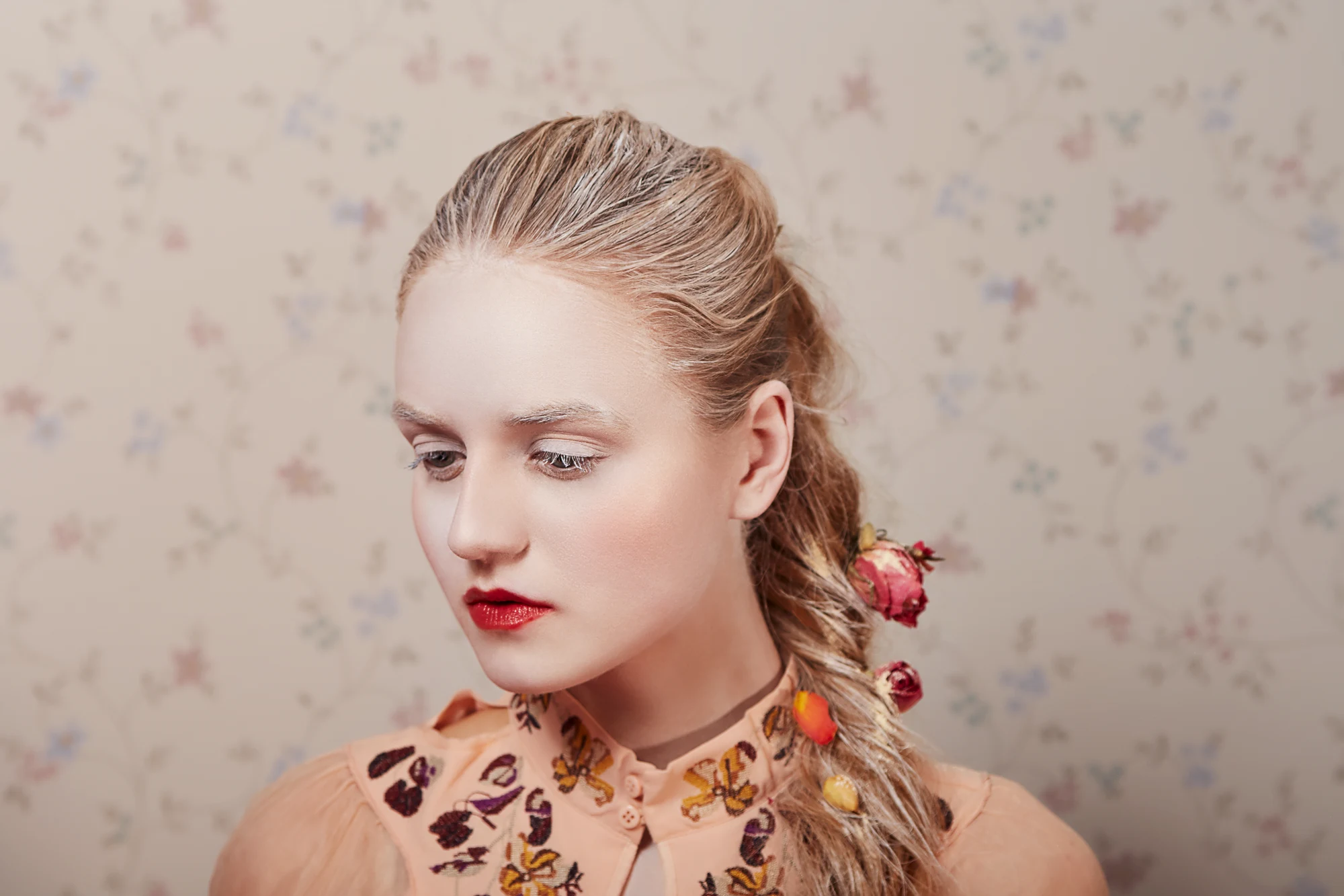 Delicate beauty portrait of a young woman with pale makeup and braid decorated with dried flowers