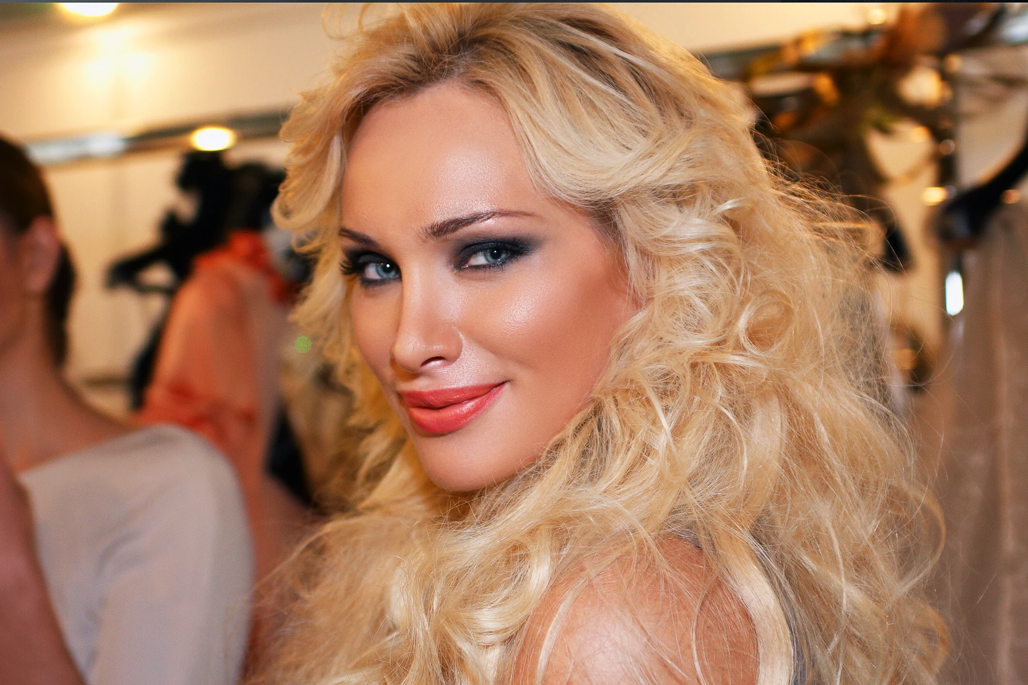 Glamorous blonde model smiling backstage at fashion event with professional makeup and hairstyle