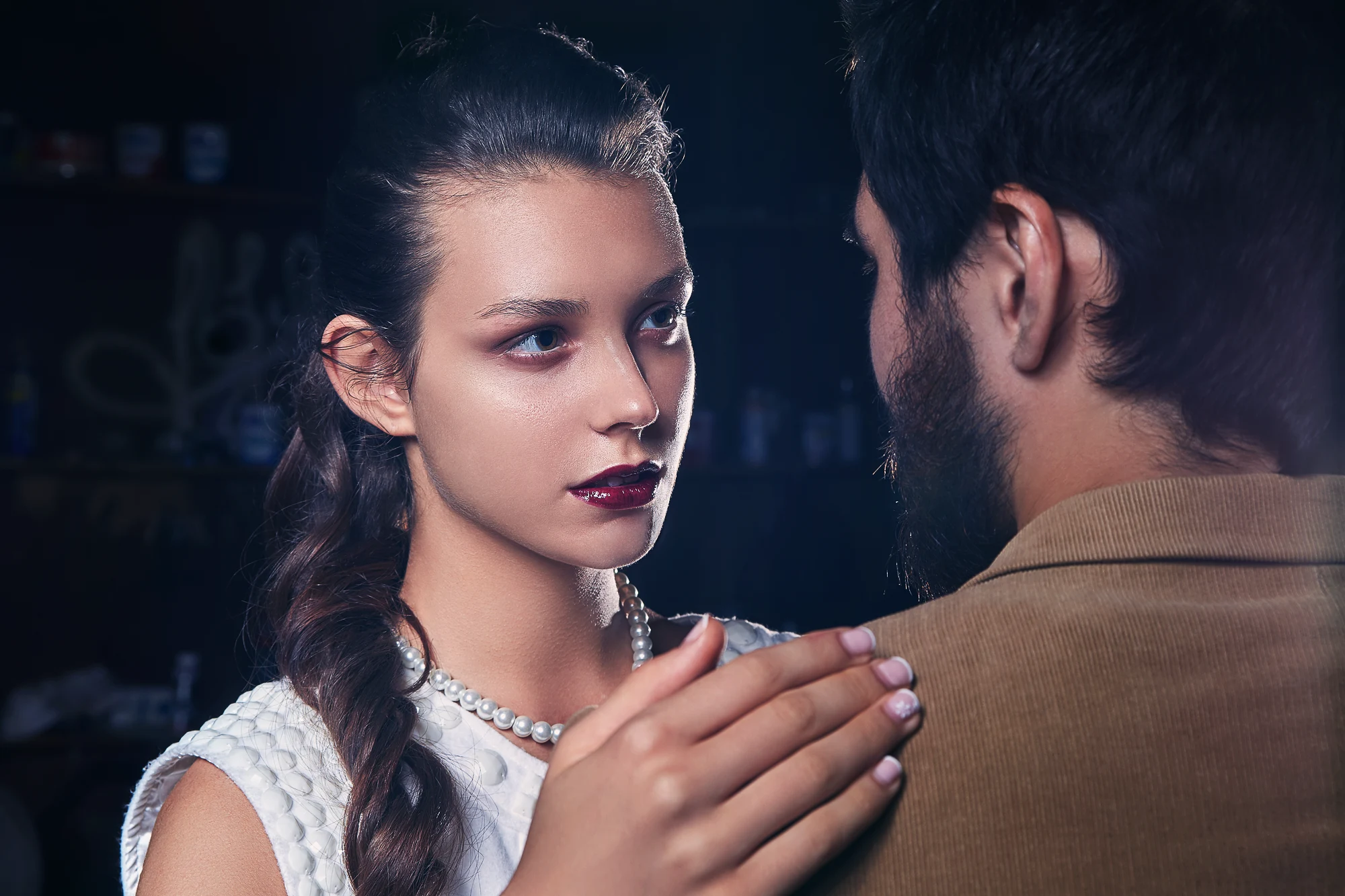 Fashion portrait photographer creating moody studio shot of young woman in lace dress with cinematic blue light