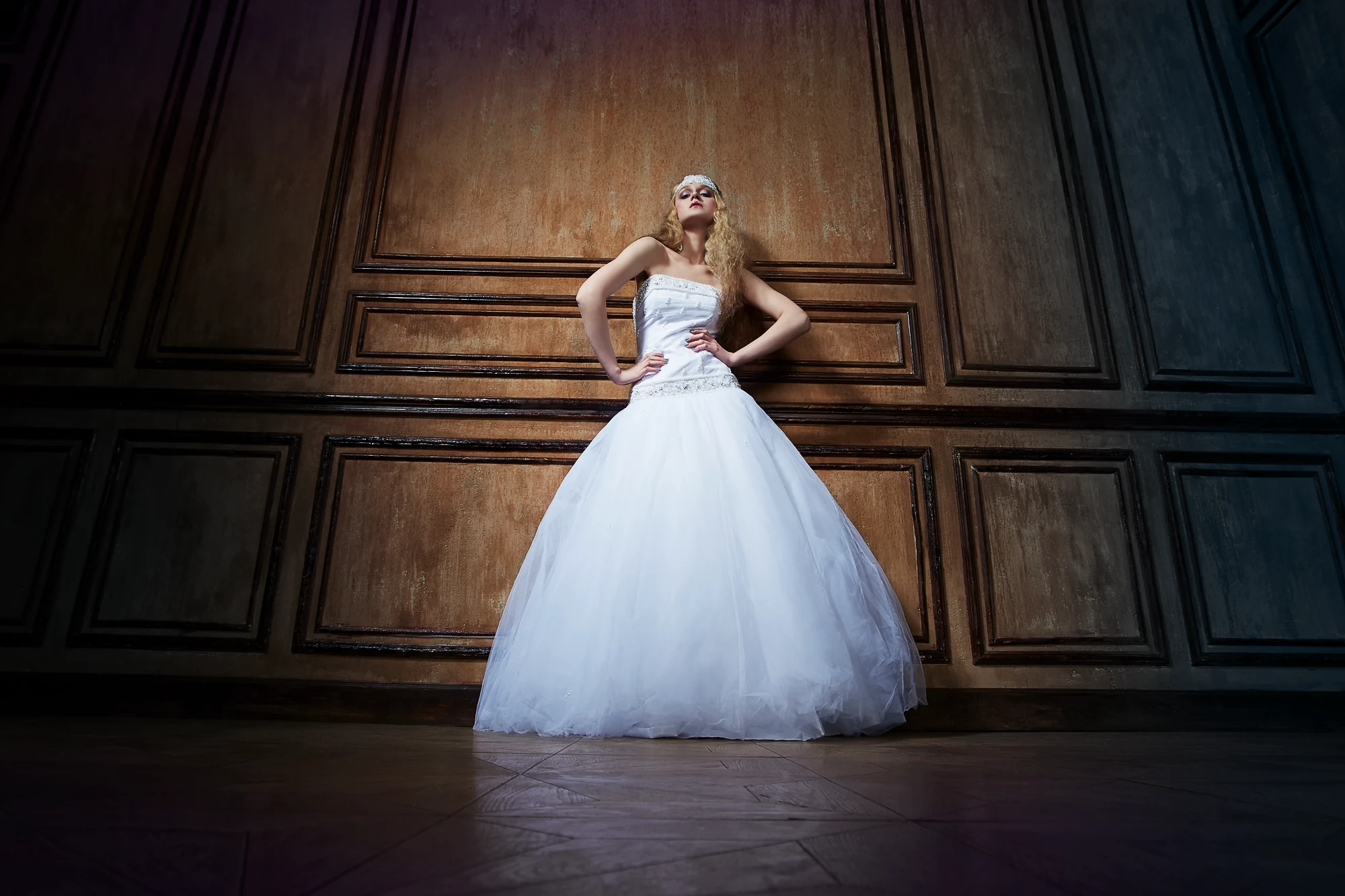 Fashion bridal portrait of tall bride in white ball gown against wooden wall, creative wedding photographer in Italy