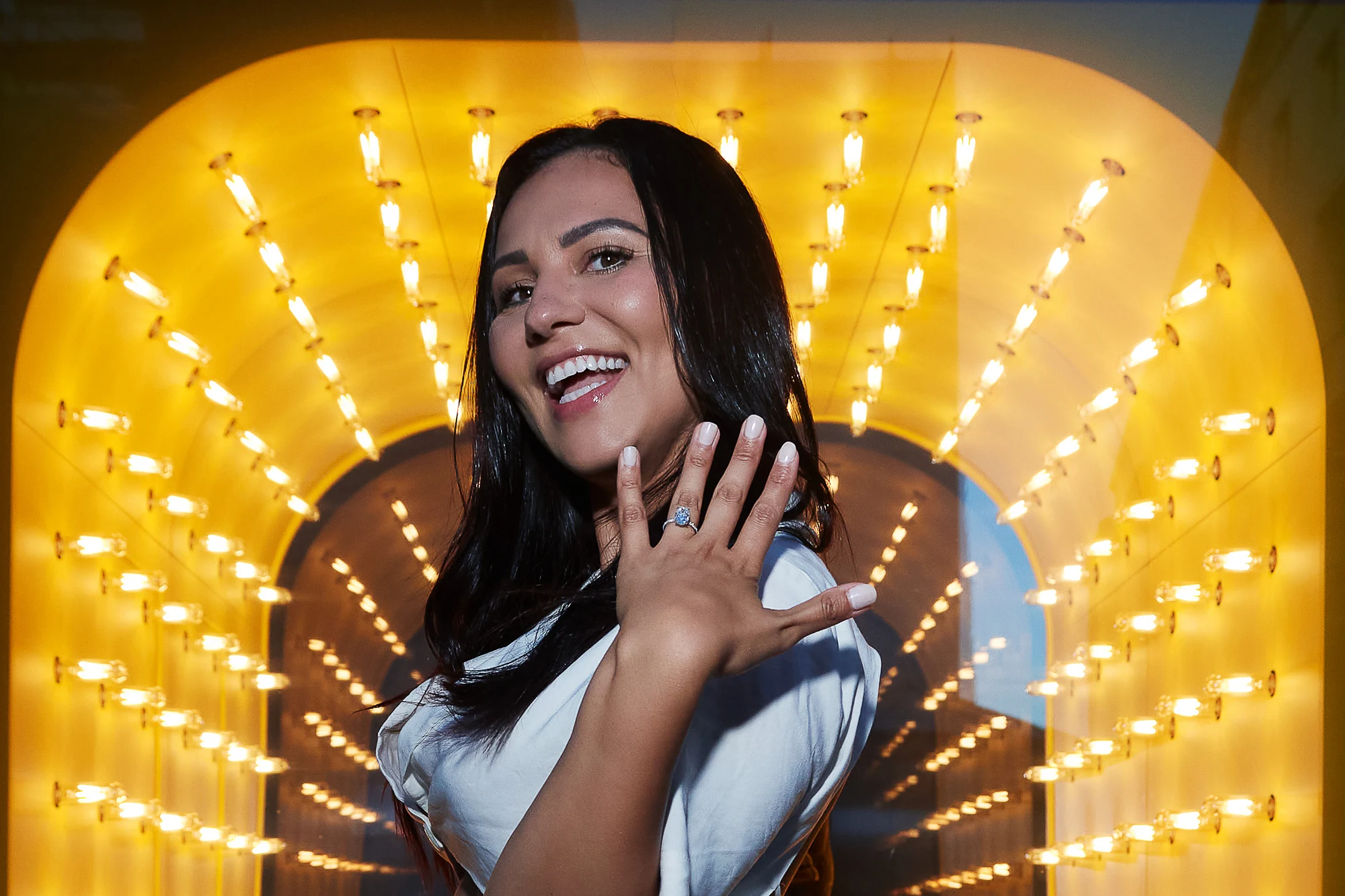 Woman showing engagement ring and smiling in glowing tunnel of lights, romantic proposal photographer in Venice Italy