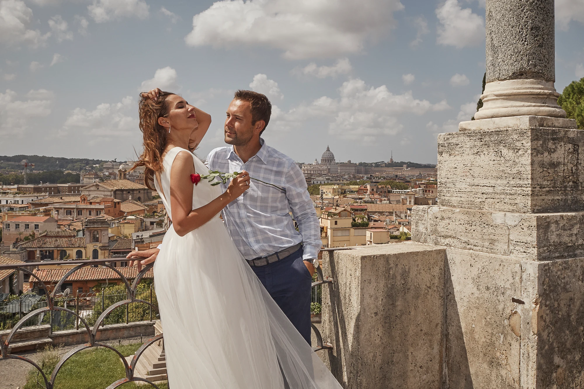 Romantic wedding couple with rose overlooking Rome skyline and Saint Peter basilica, wedding photographer in Rome Italy