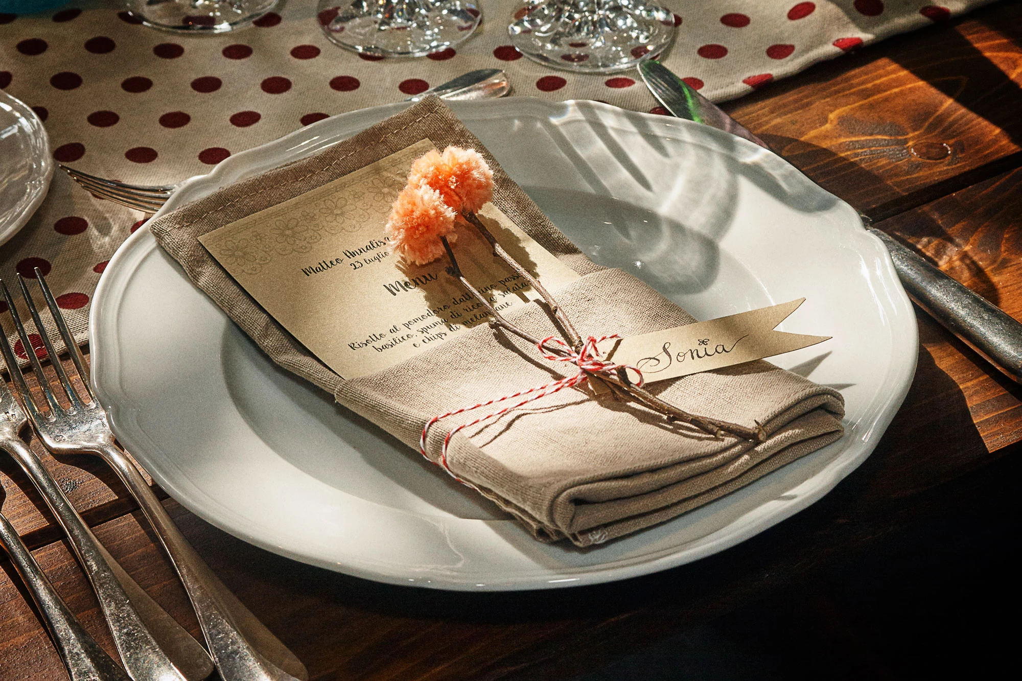 Rustic wedding table place setting with linen napkin, printed menu and name card on a wooden table