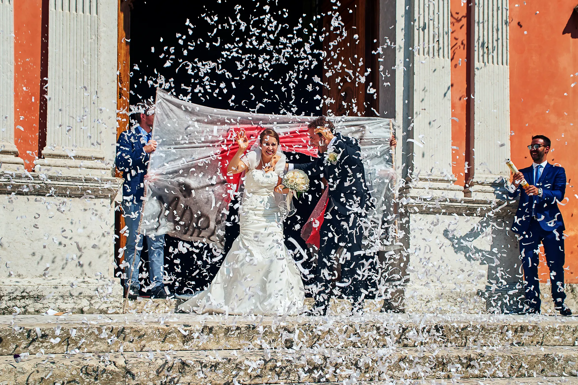 Bride and groom leaving Italian church under festive confetti shower after wedding ceremony