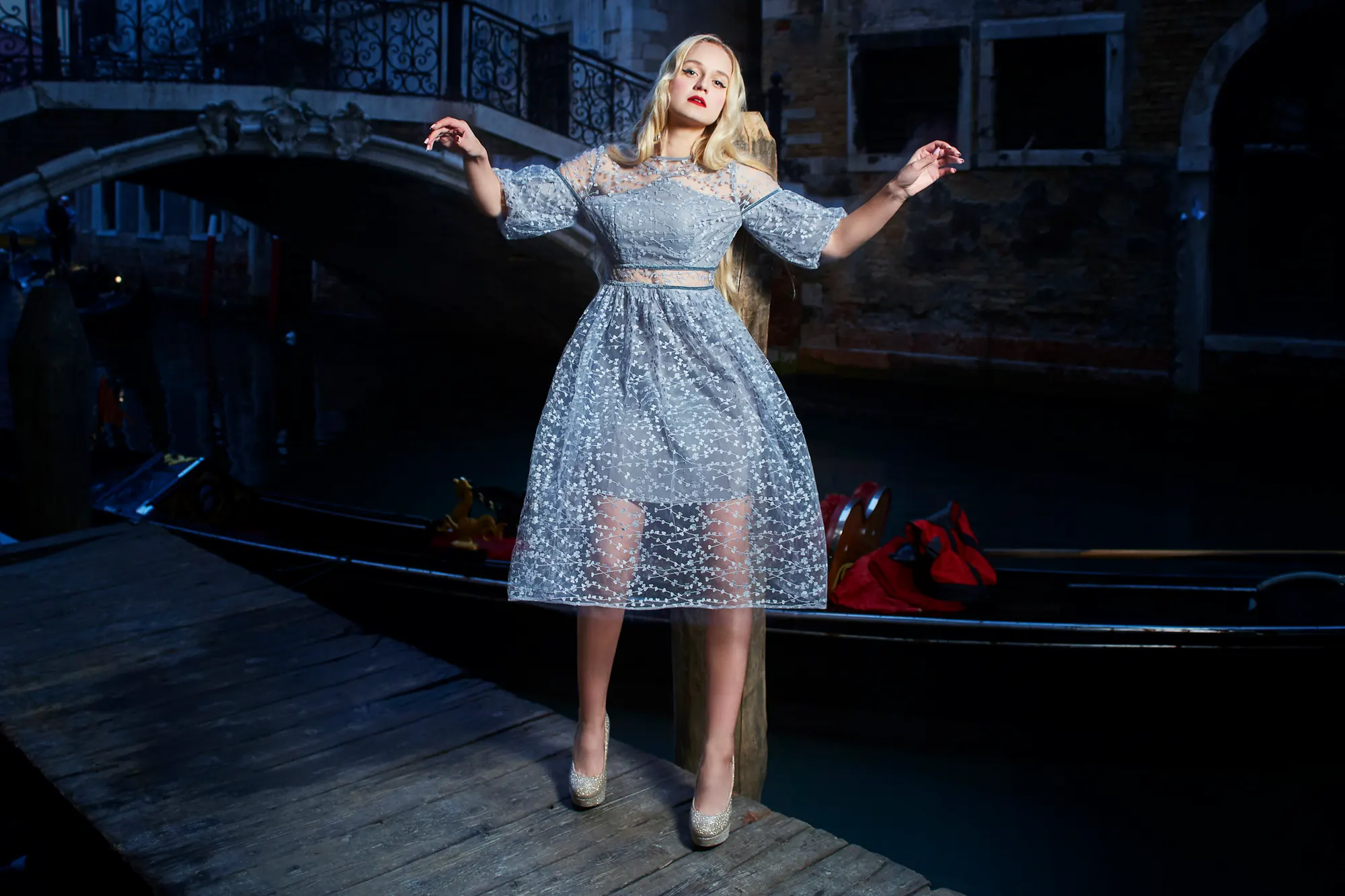 Ночной портрет элегантной женщины рядом с гондолой на тихом итальянском канале