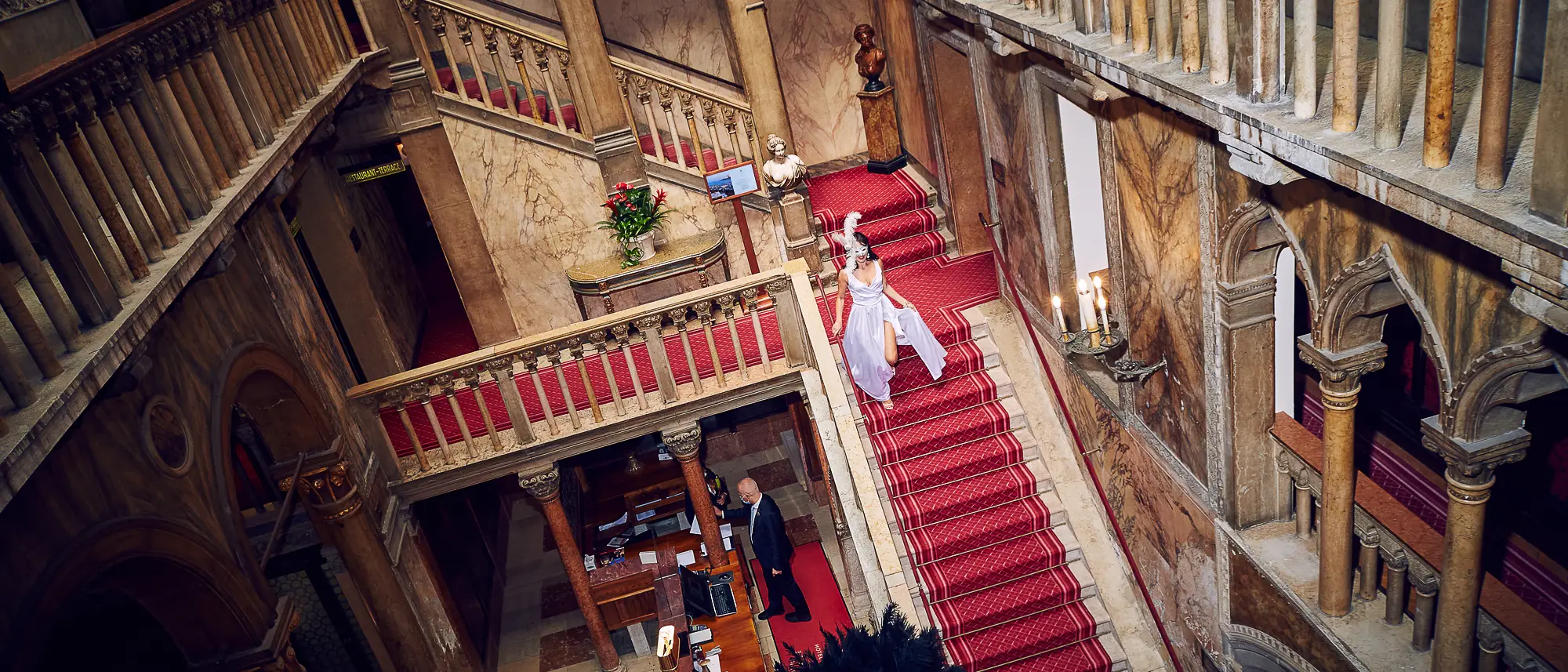 Bride in white dress walking down grand red staircase at Hotel Danieli, luxury wedding in Venice